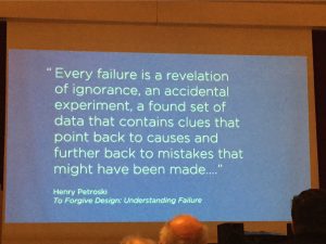 A blue slide projected on a screen reads "Every failure is a revelation of ignorance, an accidental experiment, a found set of data that contains clues that point back to causes and further back to mistake that might have been made..." Henry Petroski. to Forgive Design: Understanding Failure.