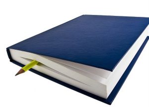 Blue covered journal with neon yellow pencil stuck in the middle of it, sticking out the end.